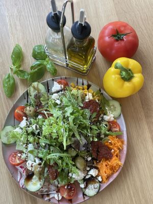 Großer gemischter Salat mit Feta, Tomaten und Oliven, frisches Gemüse als Dekoration.