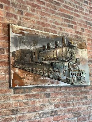 Metallisches Wandbild einer Lokomotive auf Backsteinwand im Restaurant.